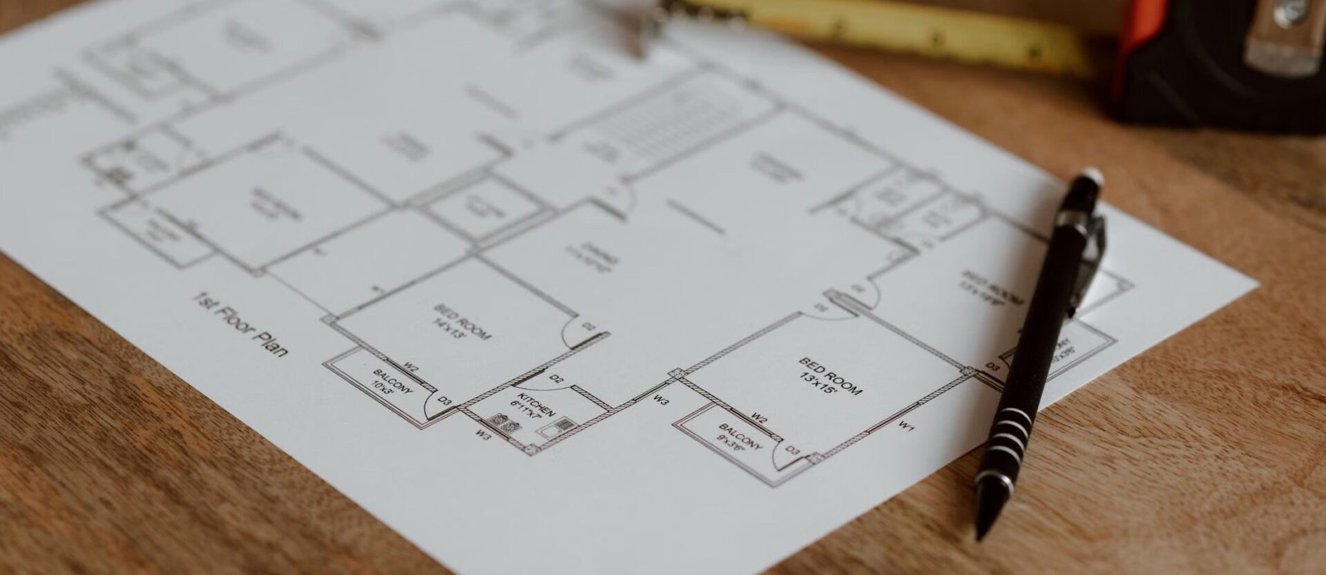 Illustrative residential floor plan with a pen and tape measure.